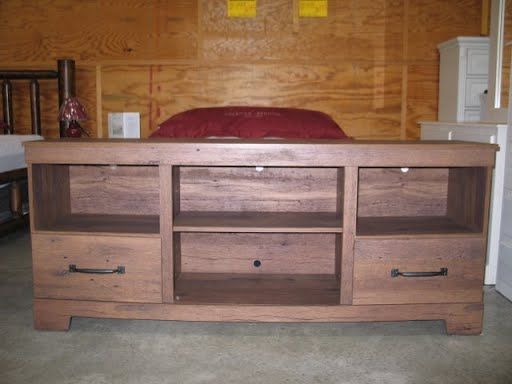 A wooden entertainment center in a room with a bed in the background