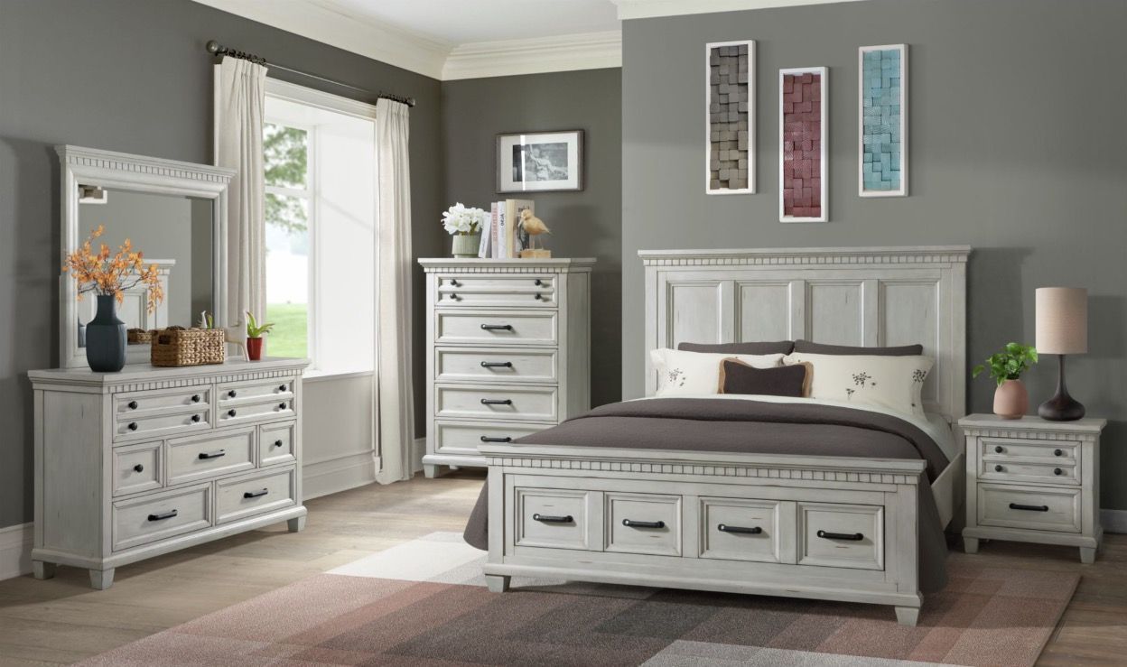A bedroom with a bed , dresser , nightstand and mirror.