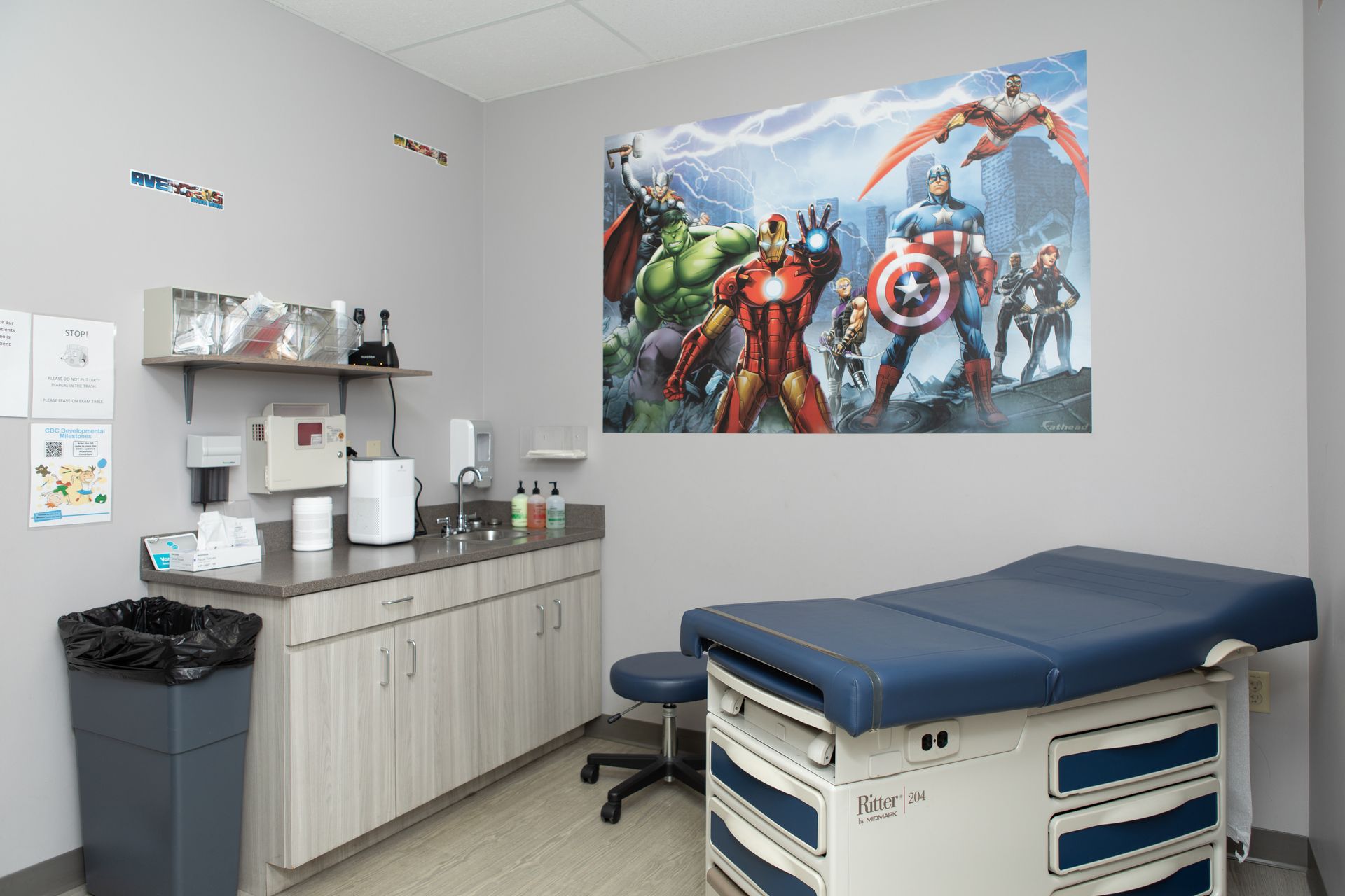 A doctor 's office with a painting of avengers on the wall.