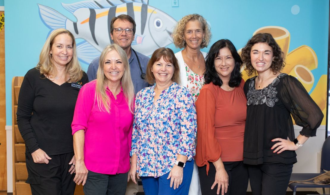 A group of people are posing for a picture in front of a mural of a fish.