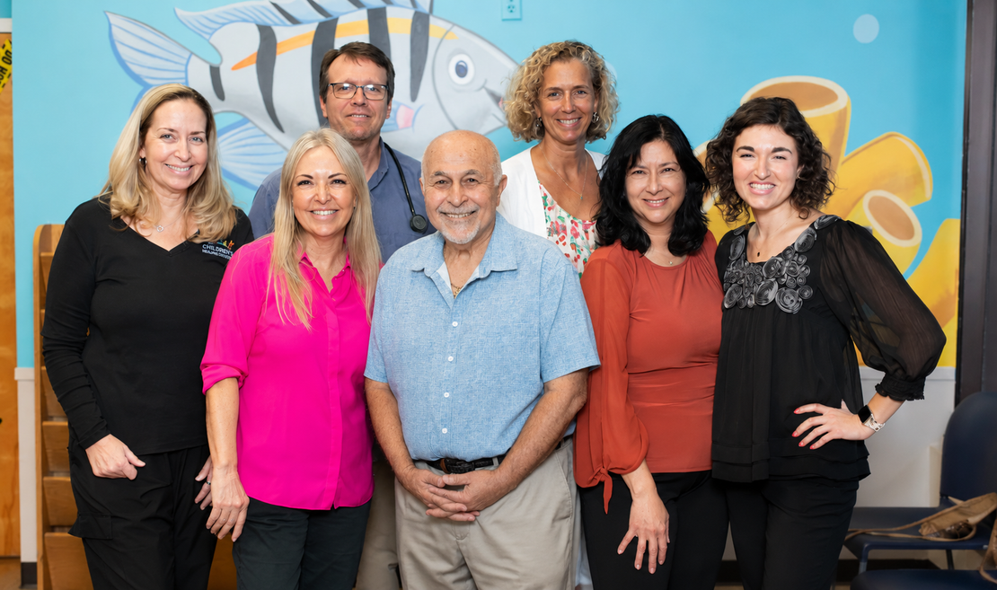 A group of people are posing for a picture in front of a mural of a fish.