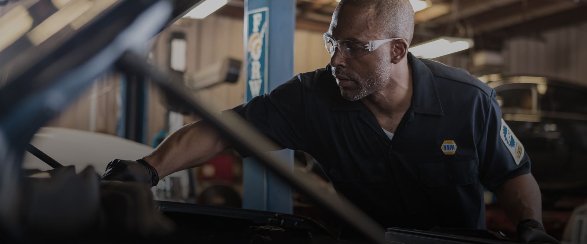 A man is working on a car in a garage. | Tom's Auto Repair and Body Shop