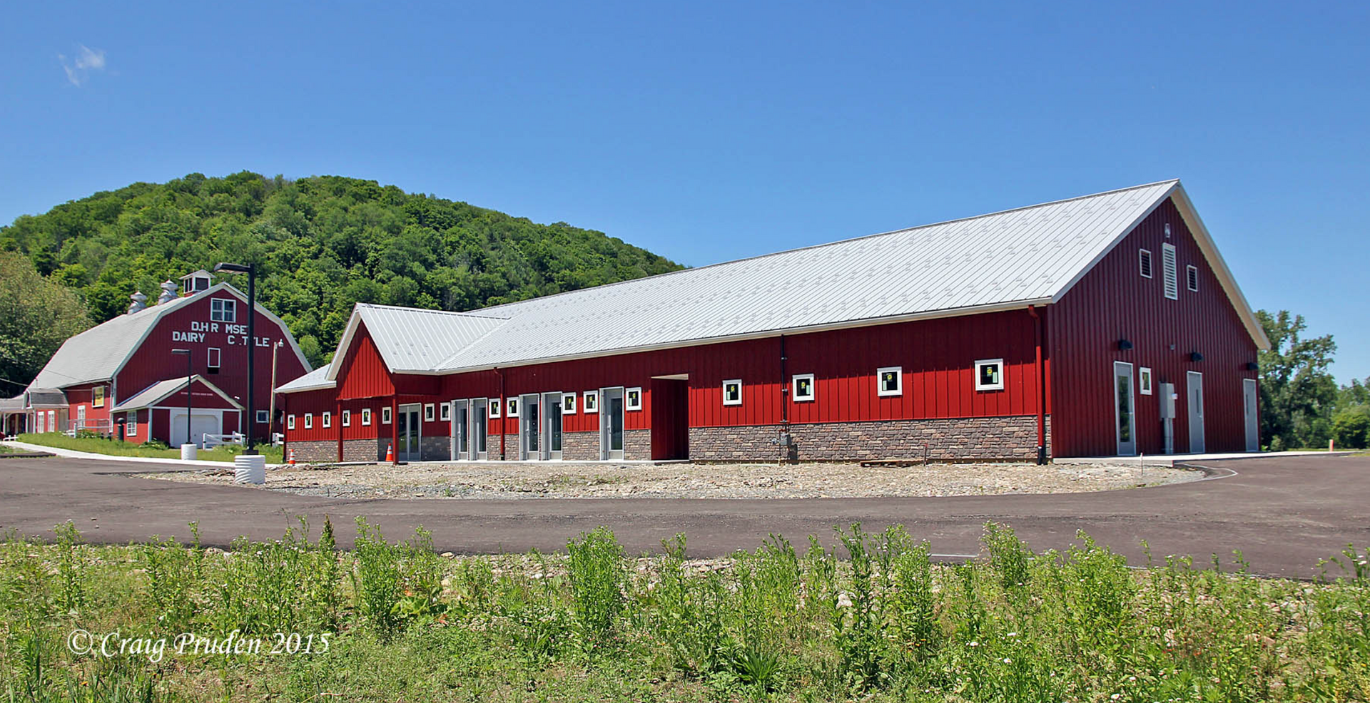 A large red barn with a white roof is next to a smaller barn