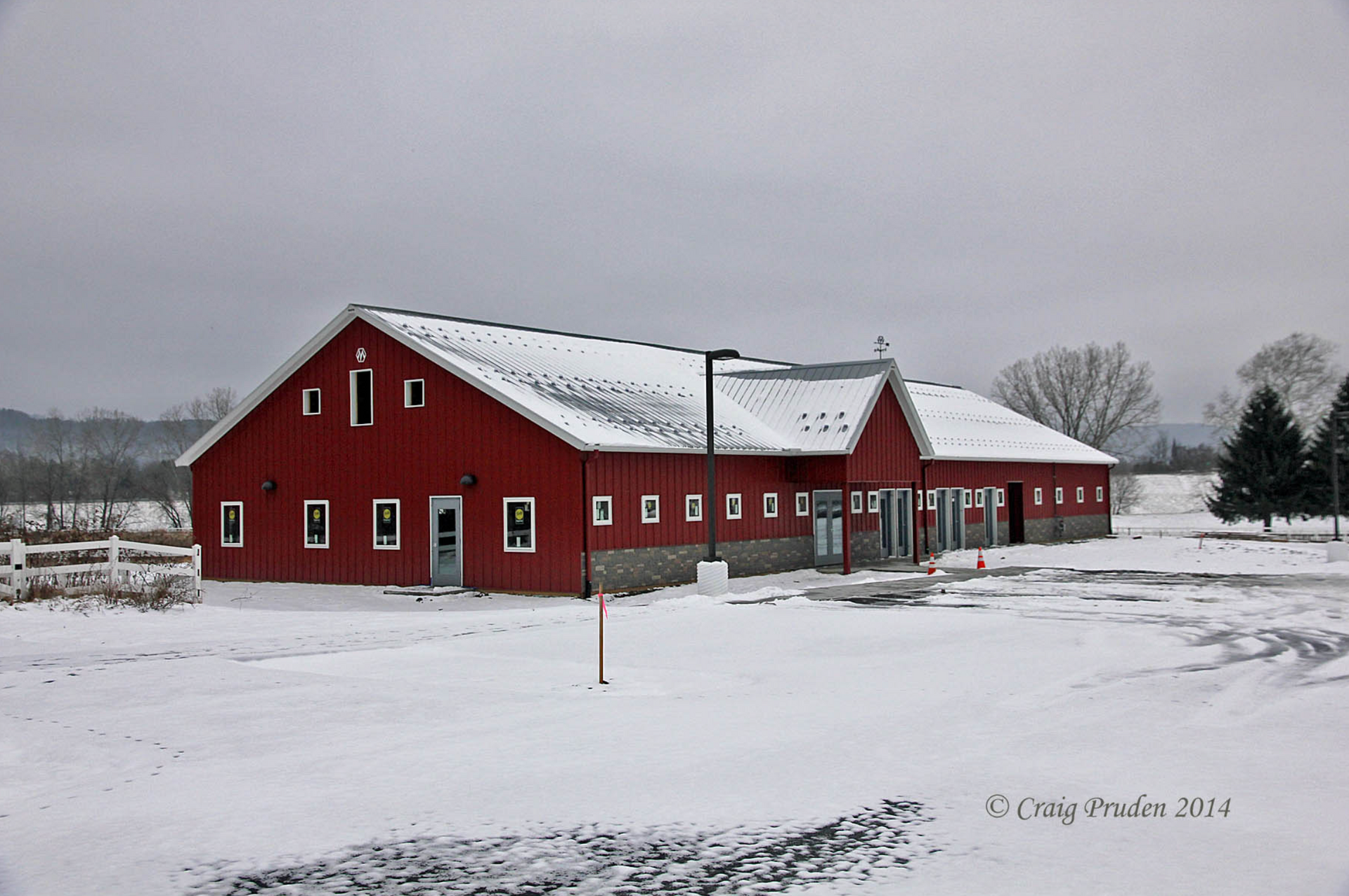 A red barn is surrounded by snow on a cloudy day
