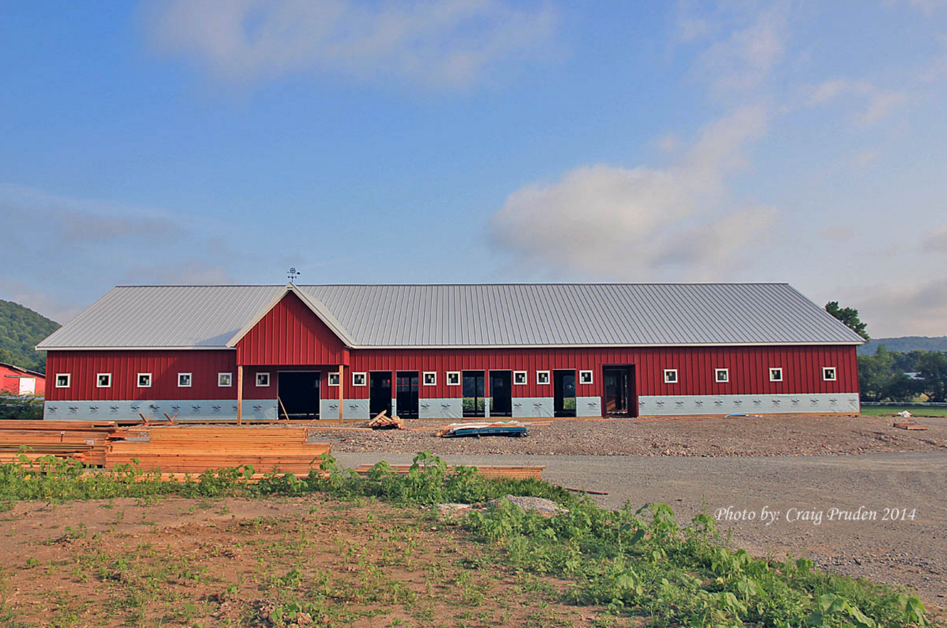 A large red barn with a white roof is being built