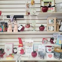 Shelves of trinkets: apples, gnomes, candles, books, and decorative objects in a retail setting.