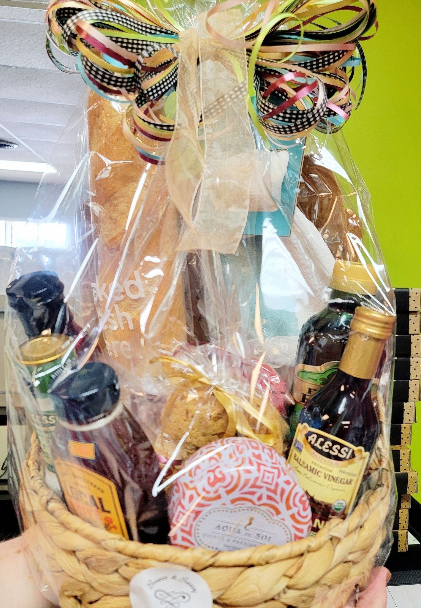 Gift basket with bread, bottles, and decorative bow.