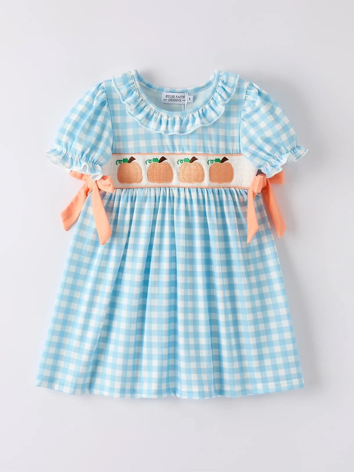 Blue gingham girl's dress with pumpkin smocking, ruffle collar, and peach bows on sleeves.