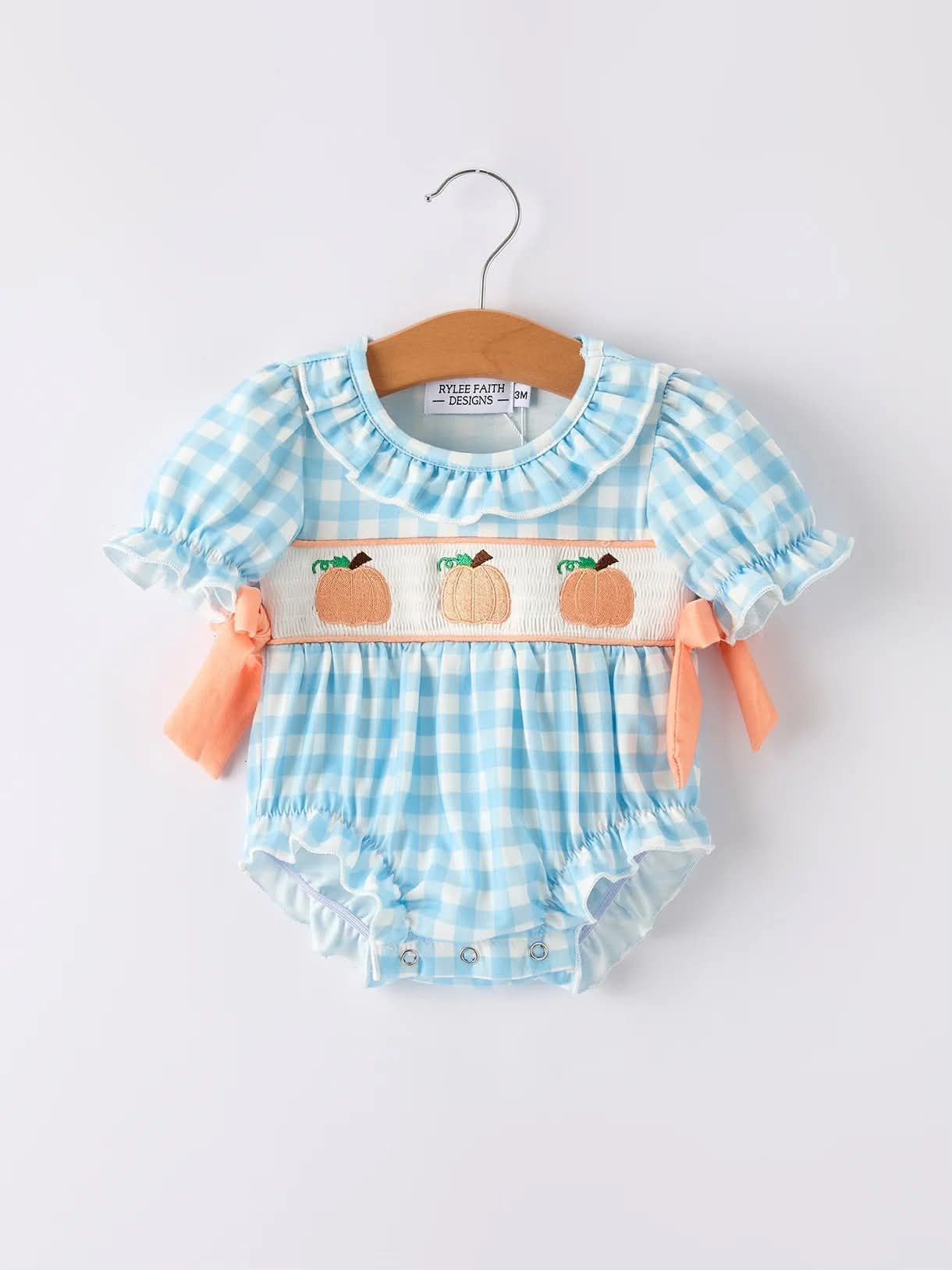 Baby blue gingham romper with pumpkin embroidery, ruffle sleeves and ties.