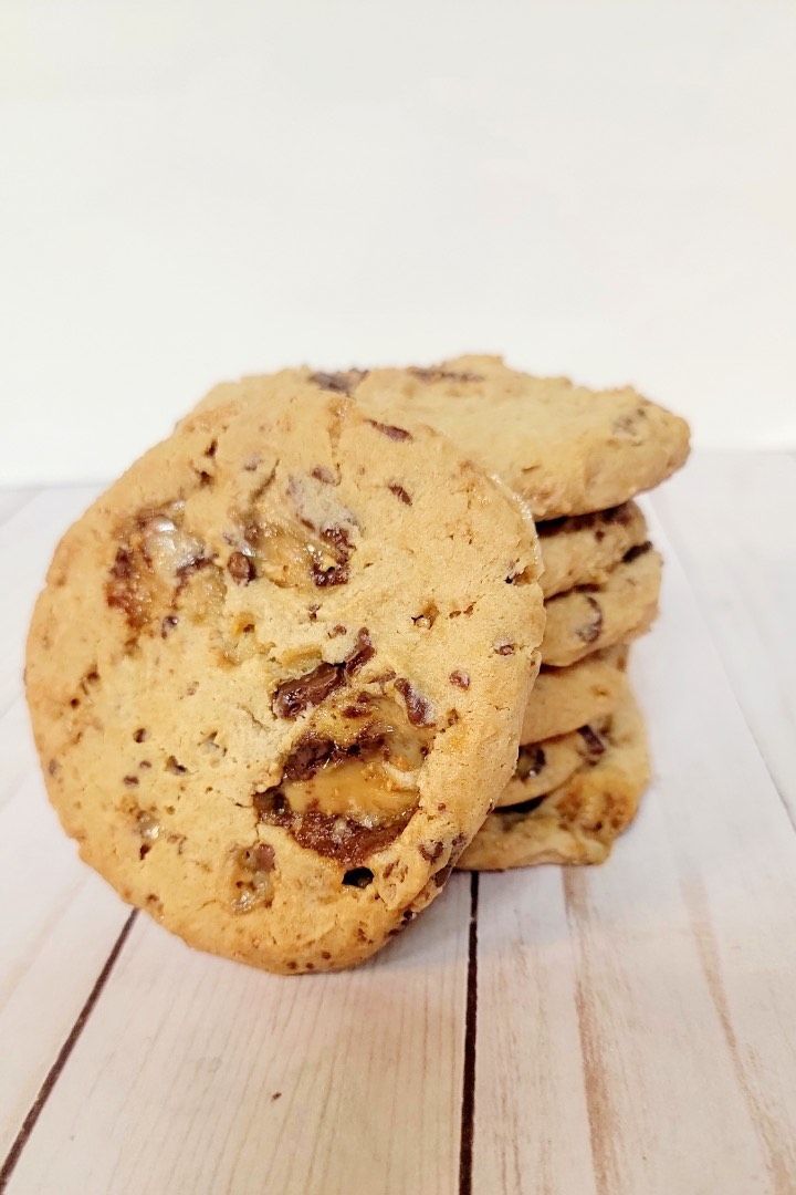 Stack of chocolate chip cookies on a light wooden surface.