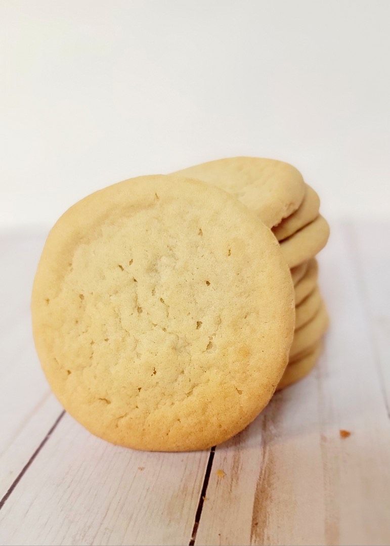 Stack of light brown, round cookies on a light-colored wood surface.
