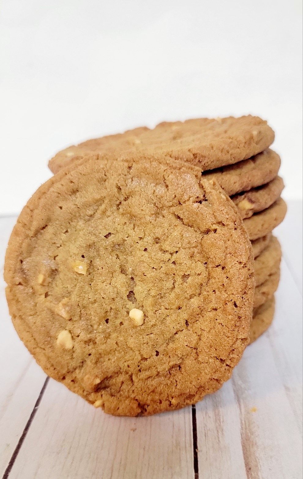 Stack of golden brown cookies with white specks on a light wood surface.