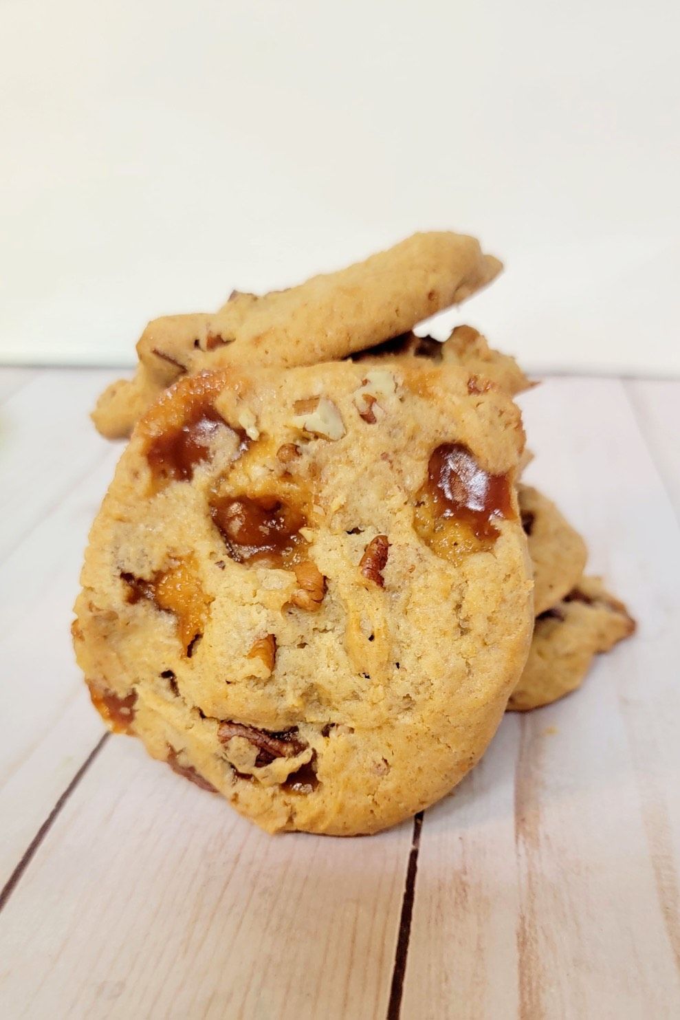 Stack of caramel cookies on a light wooden surface.