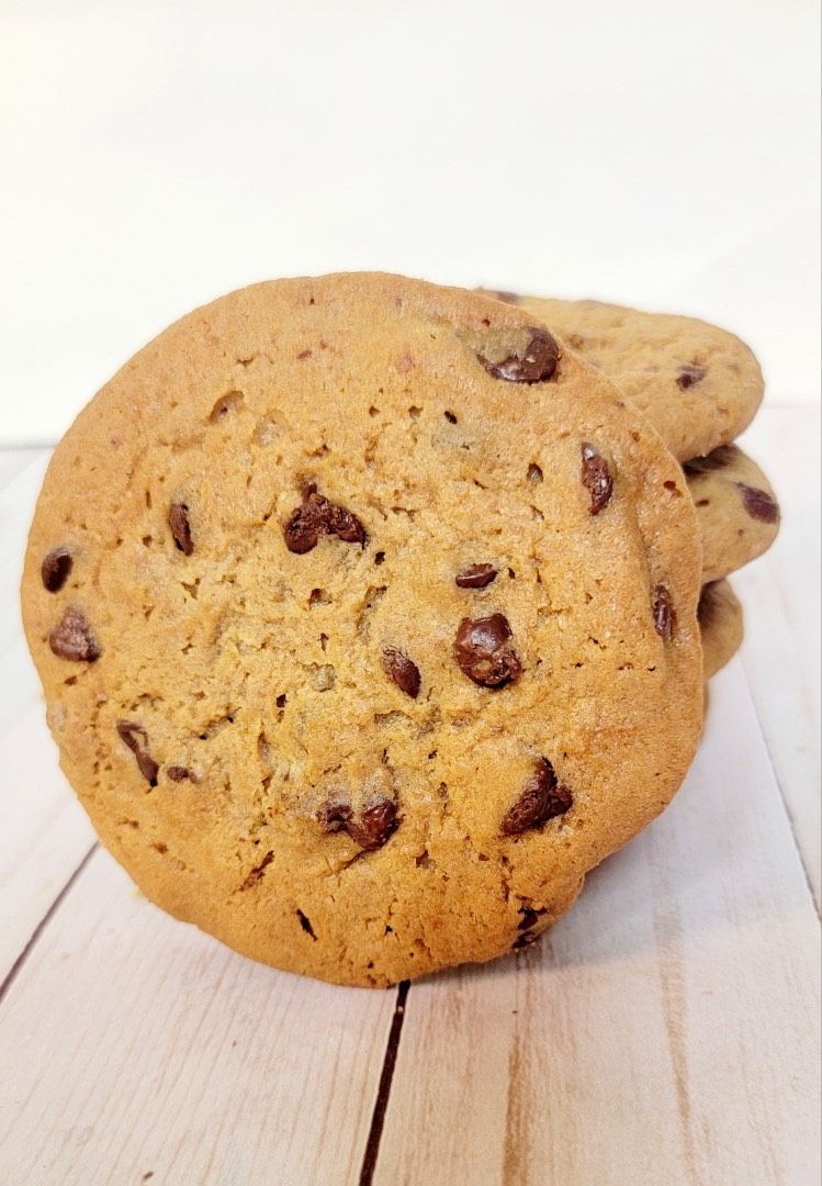 Stack of chocolate chip cookies on a white wooden surface.