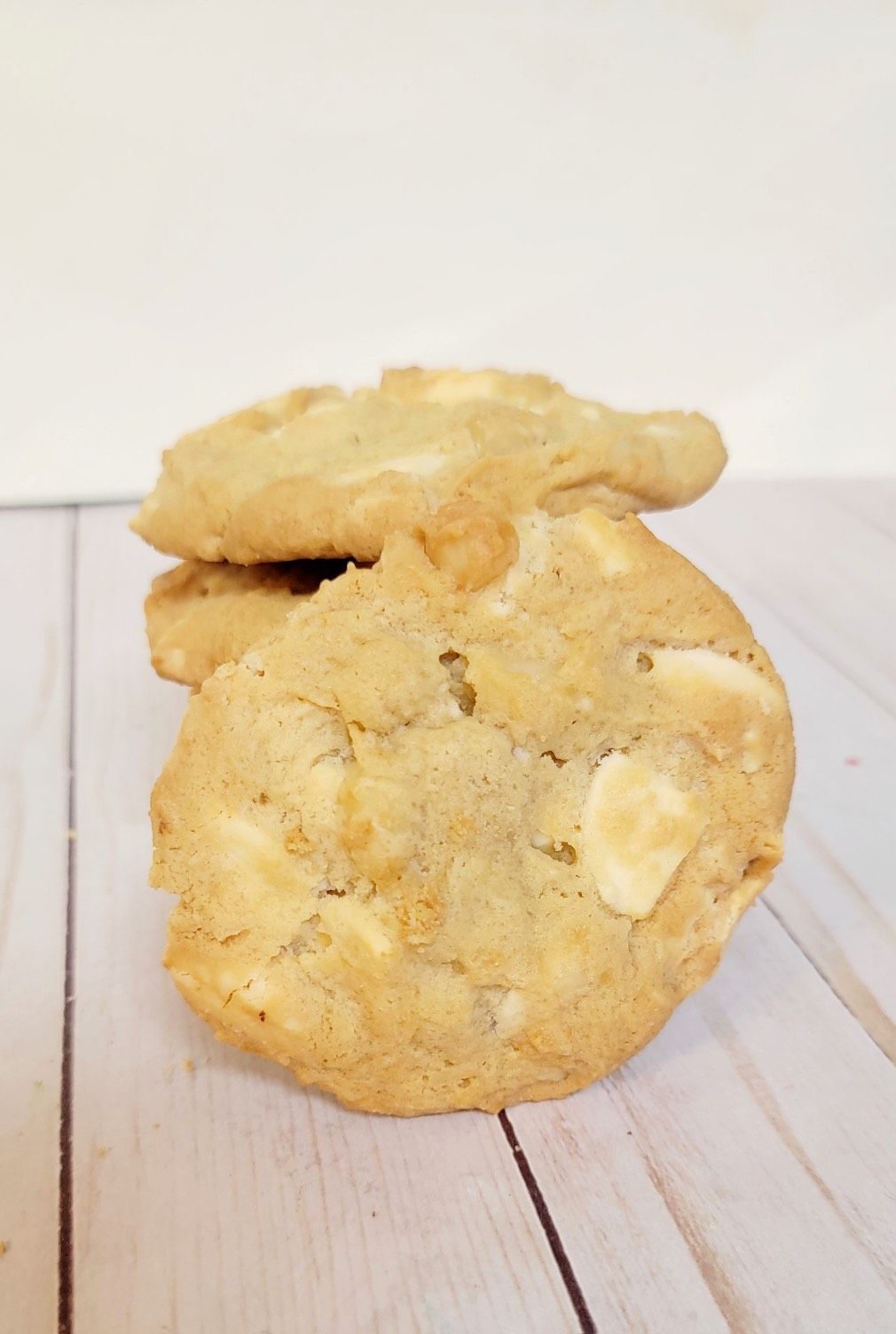 Stack of white chocolate chip cookies on a light wood background.