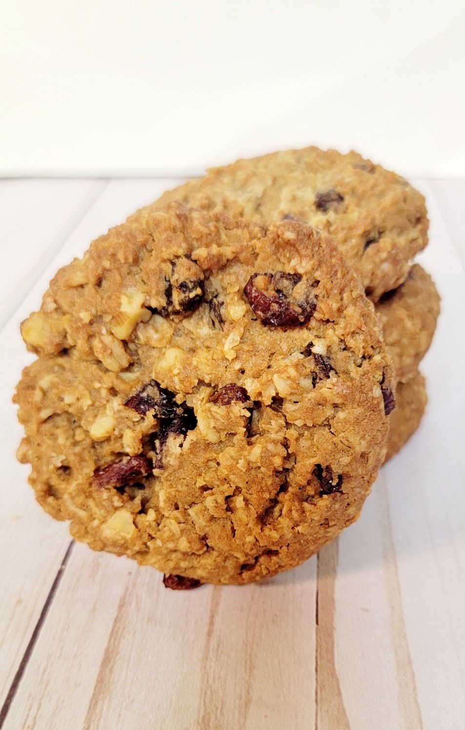 Stack of oatmeal raisin cookies on a light wooden surface.