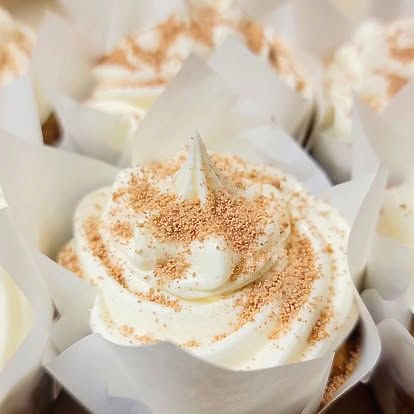 Cupcakes with white frosting and brown sprinkles in white paper liners.
