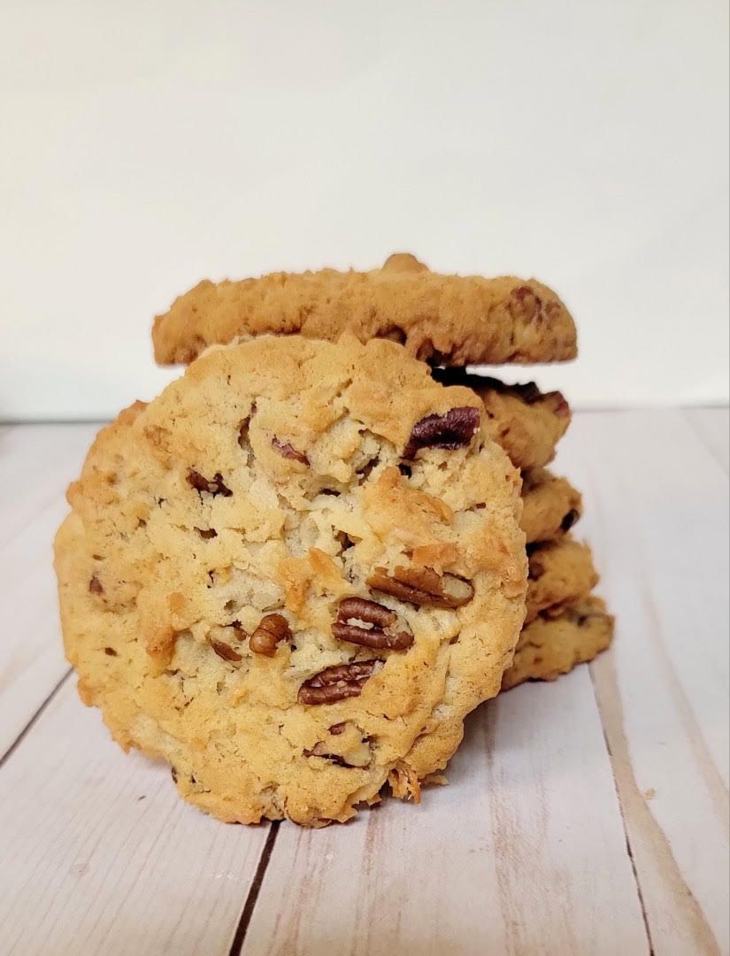 Stack of round cookies with pecans, on a light wood surface.