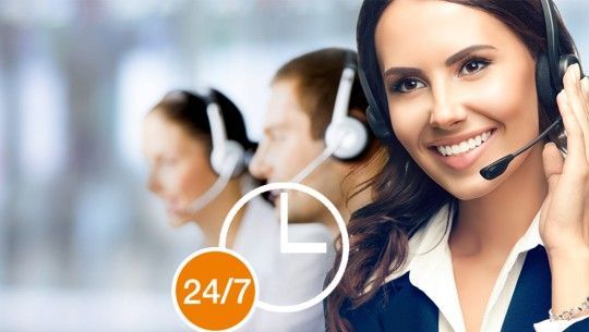 a woman wearing a headset with a 24/7 sign in the background