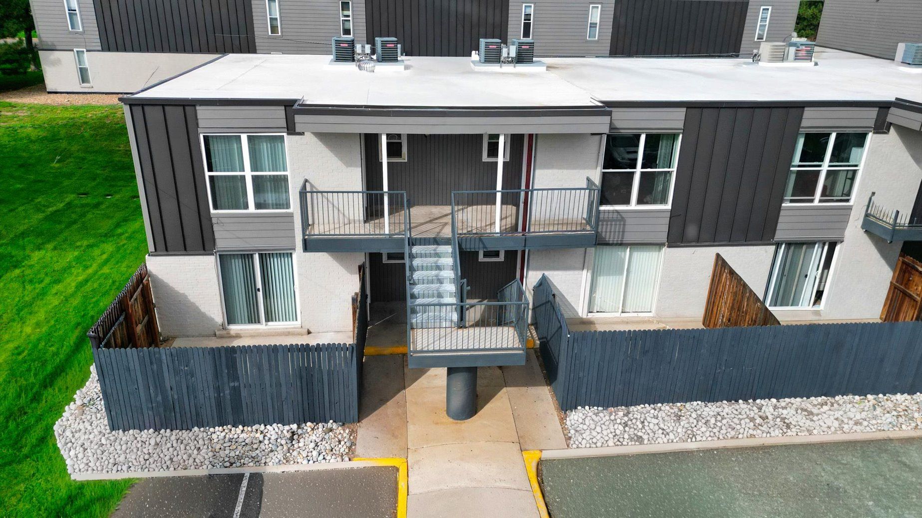 Apartment building exterior with balconies, gray siding, and a central staircase.