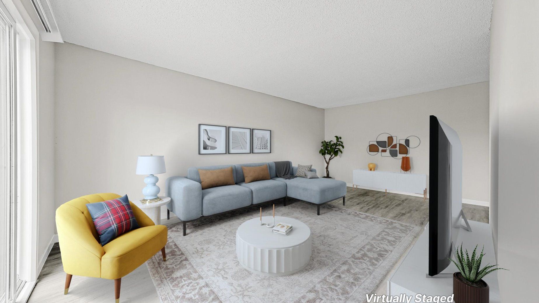 Modern apartment living room with light blue sectional, yellow accent chair, coffee table, and TV.