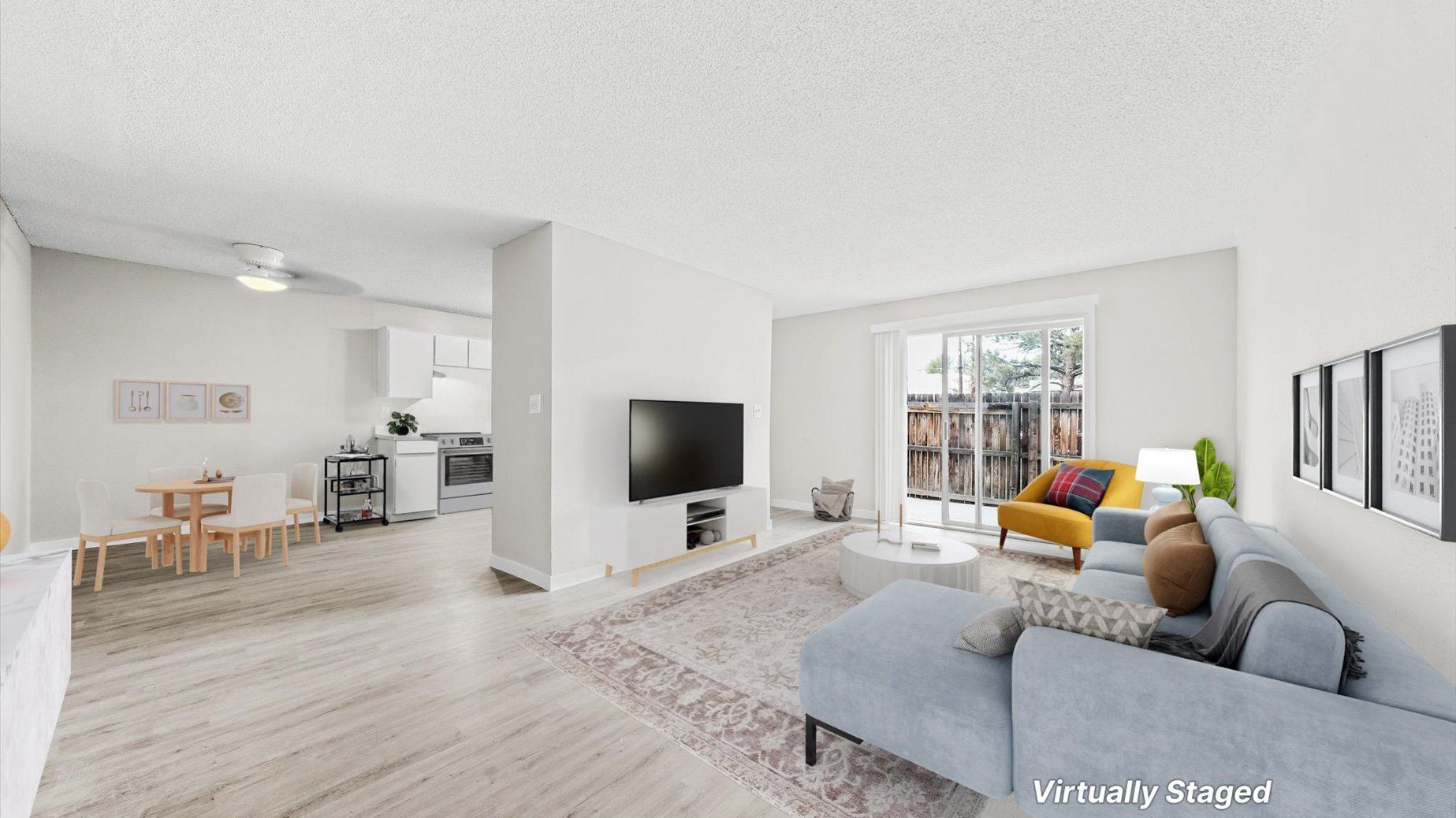 Open-concept living room with sofa, TV, dining table, and kitchen.