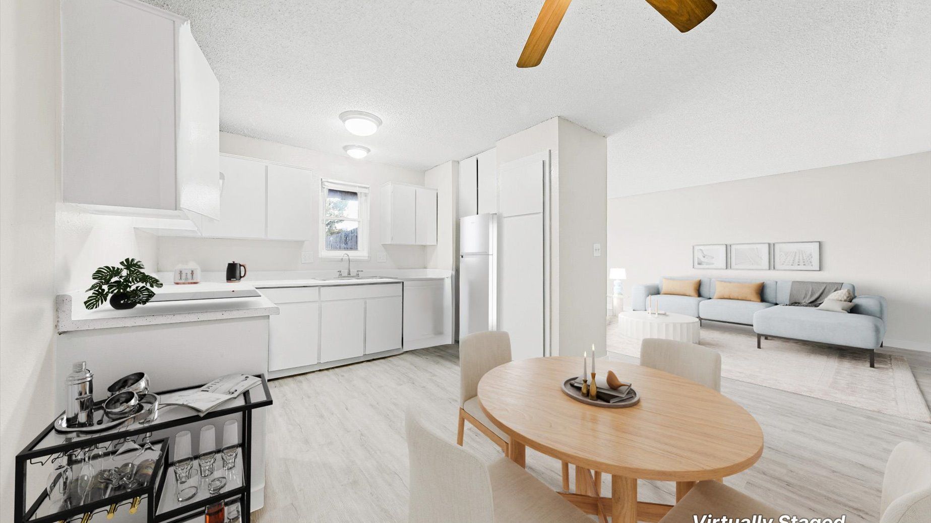 Bright open-concept apartment interior with white kitchen and living area.