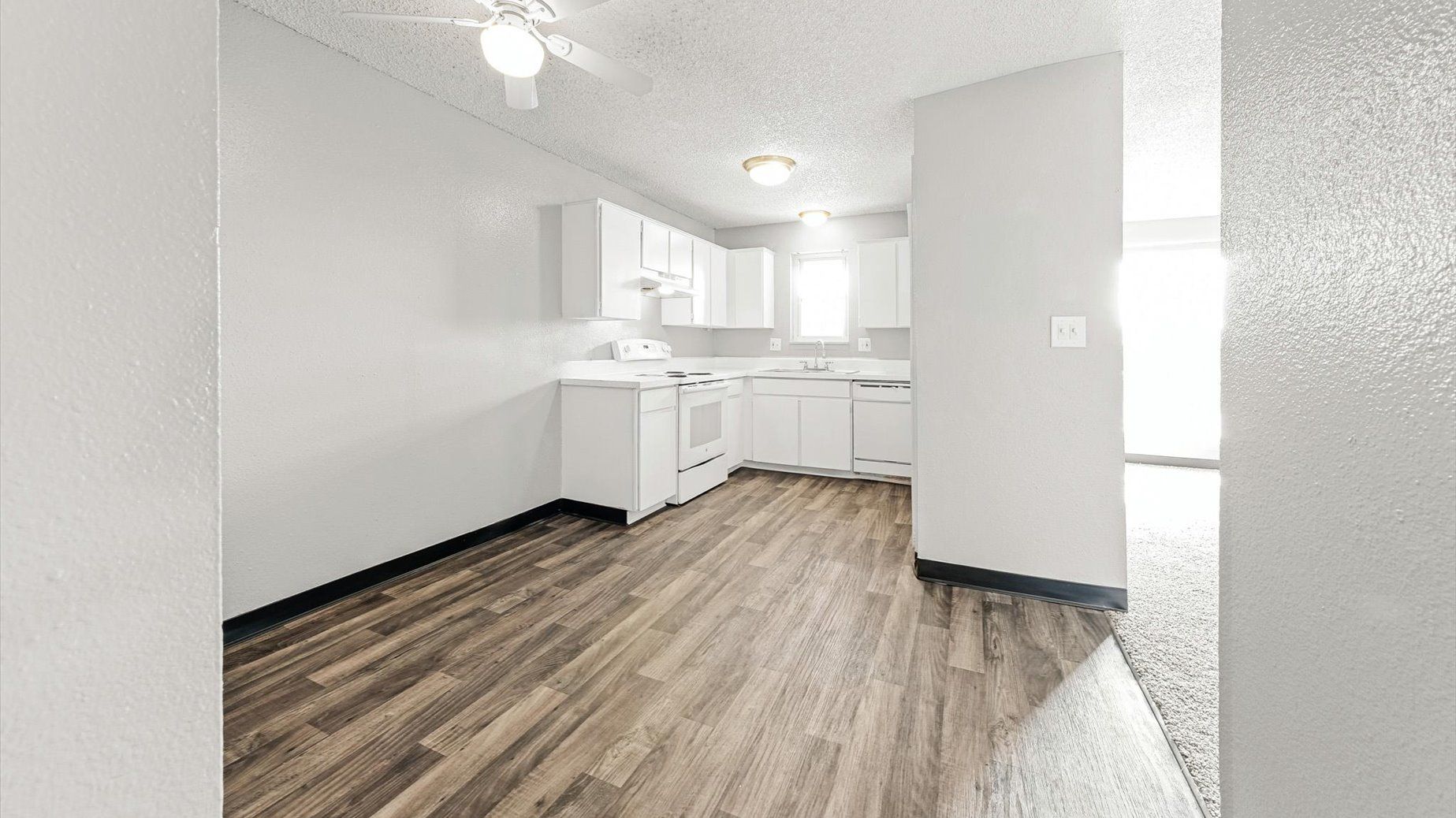 White kitchen with cabinets, stove, sink, and dishwasher.