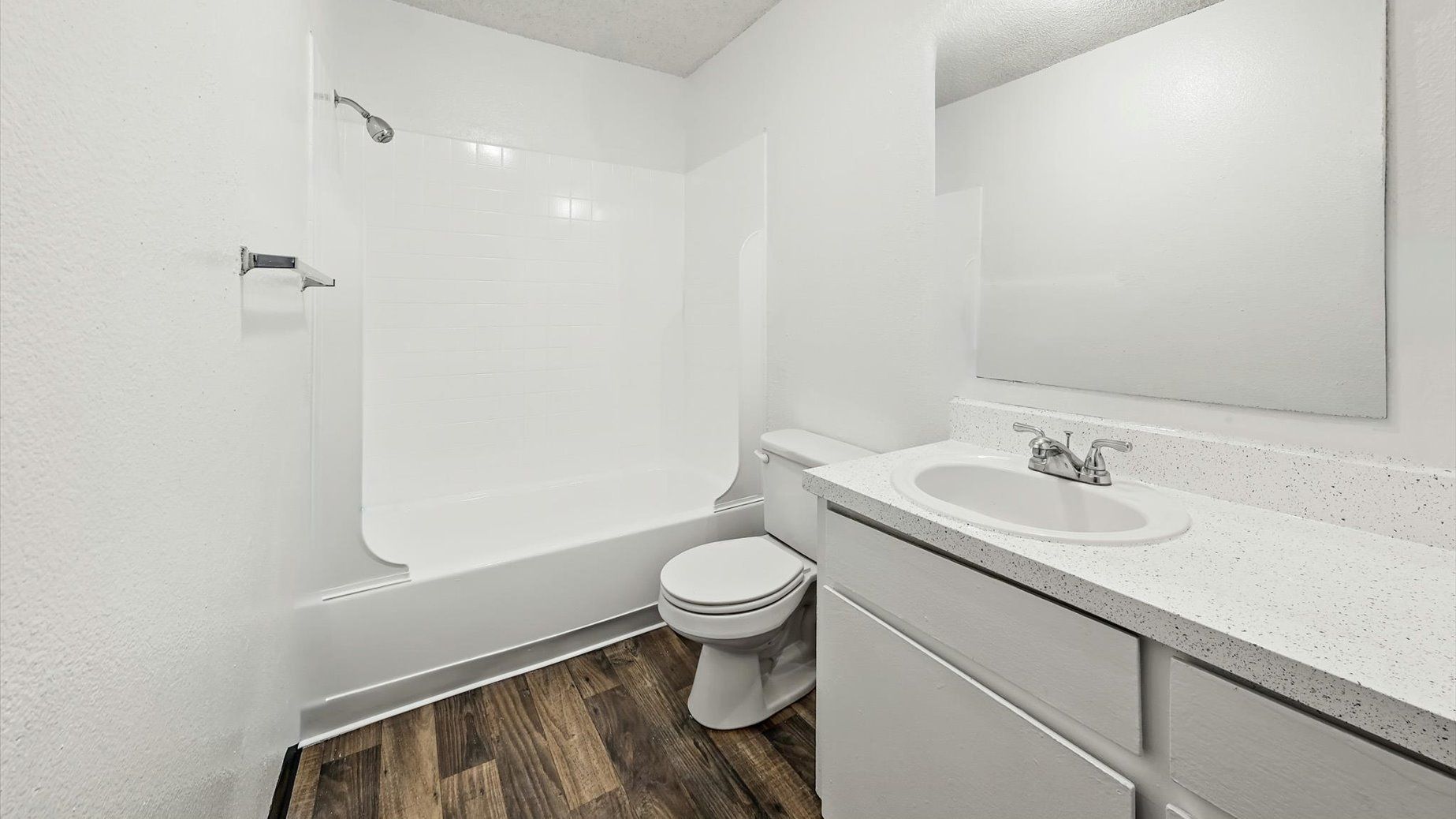 White bathroom with tub/shower combo, toilet, and vanity.