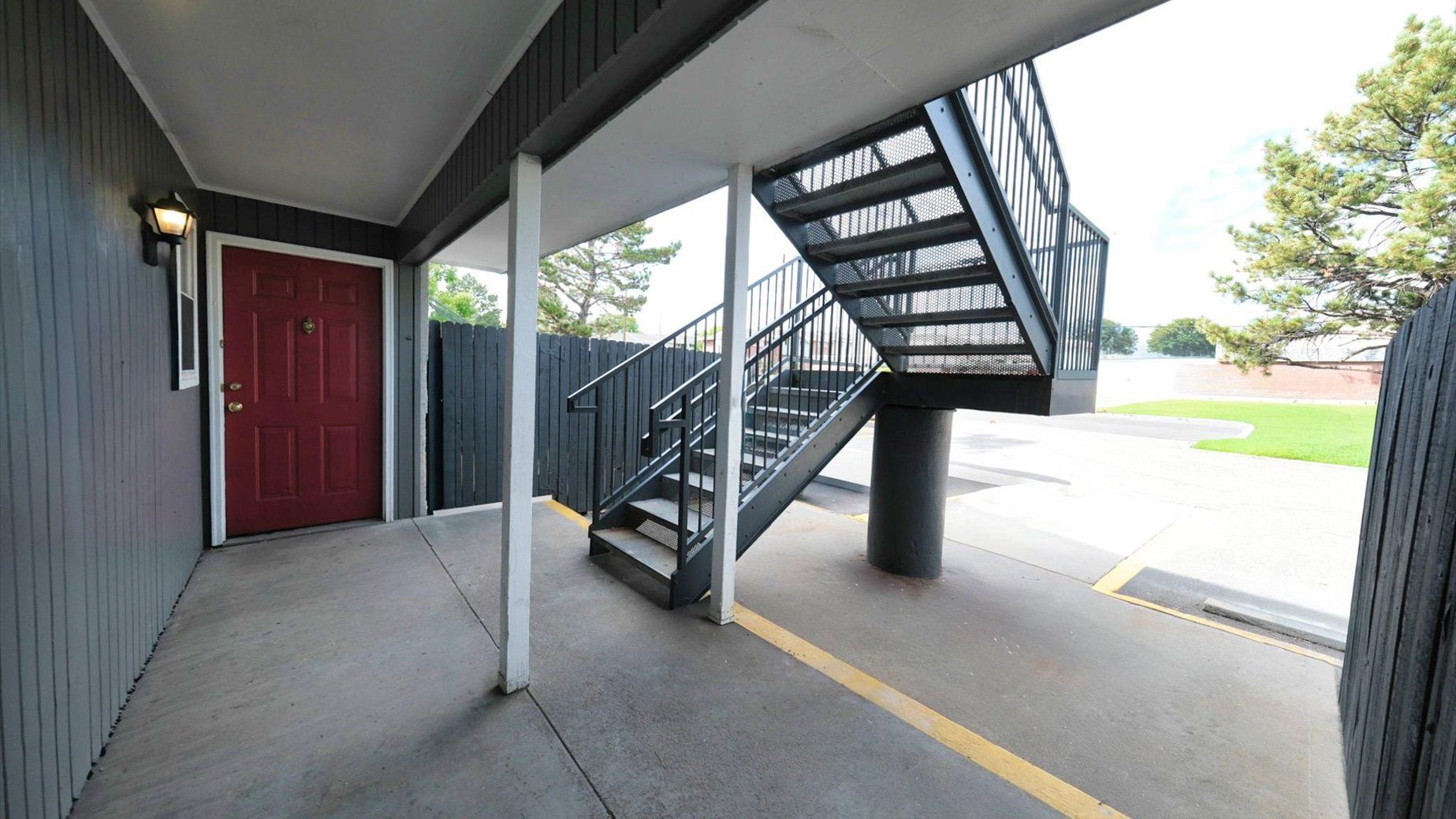Exterior stairwell and ground-floor apartment entry under a covered walkway.