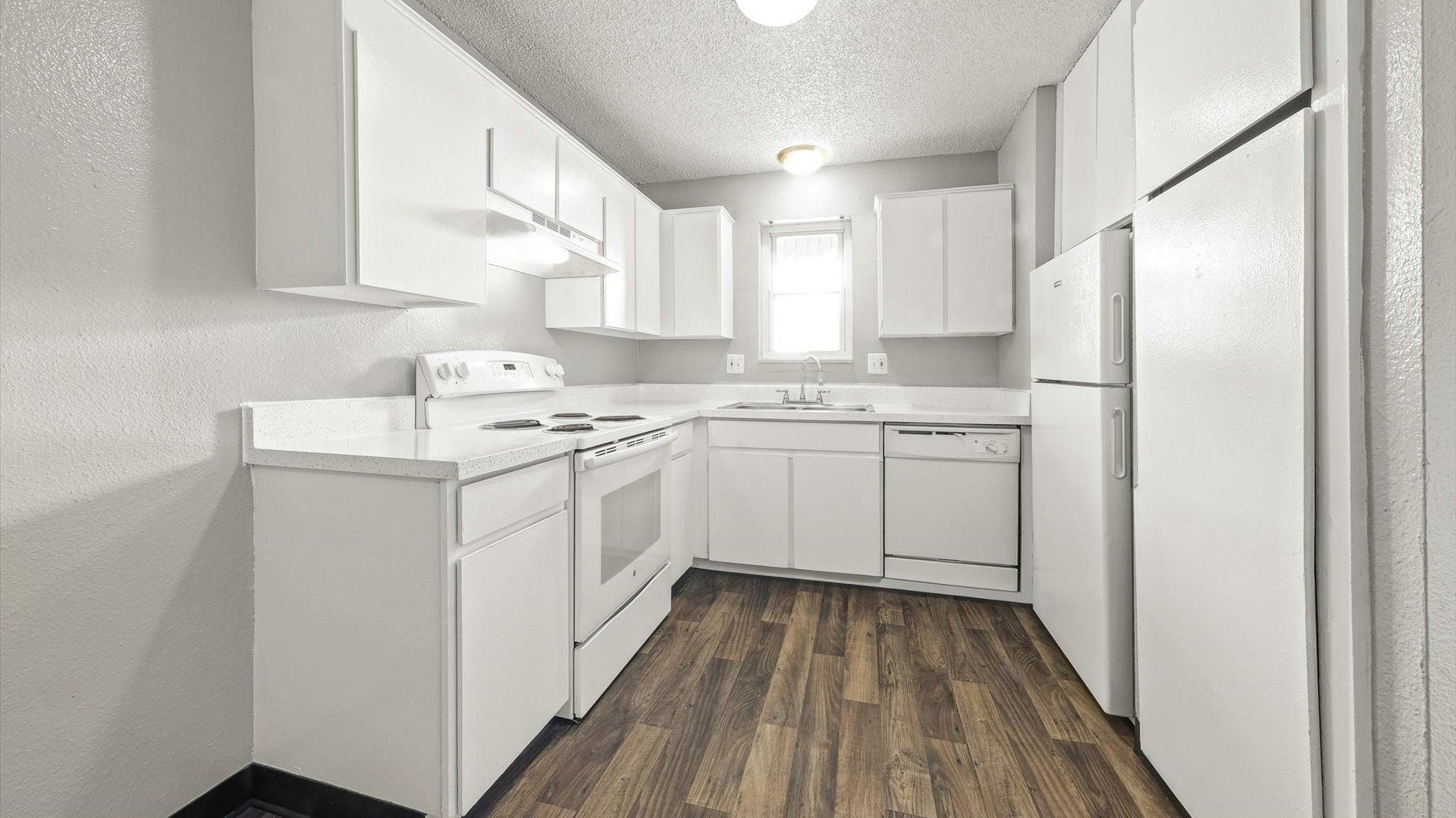 White kitchen with upper and lower cabinets, stove, dishwasher, and refrigerator.