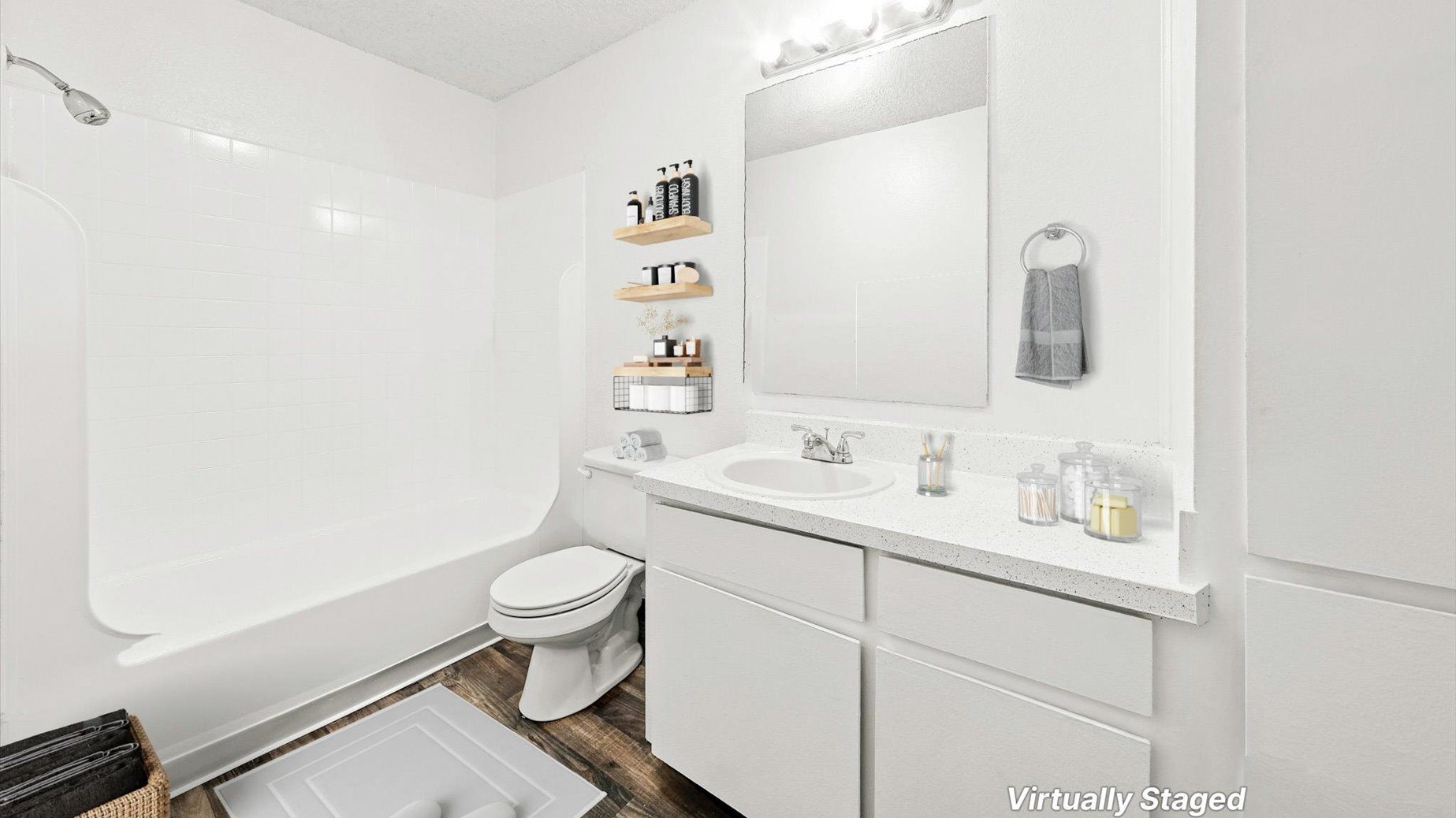 White bathroom with sink vanity, mirror, toilet, and bathtub/shower.