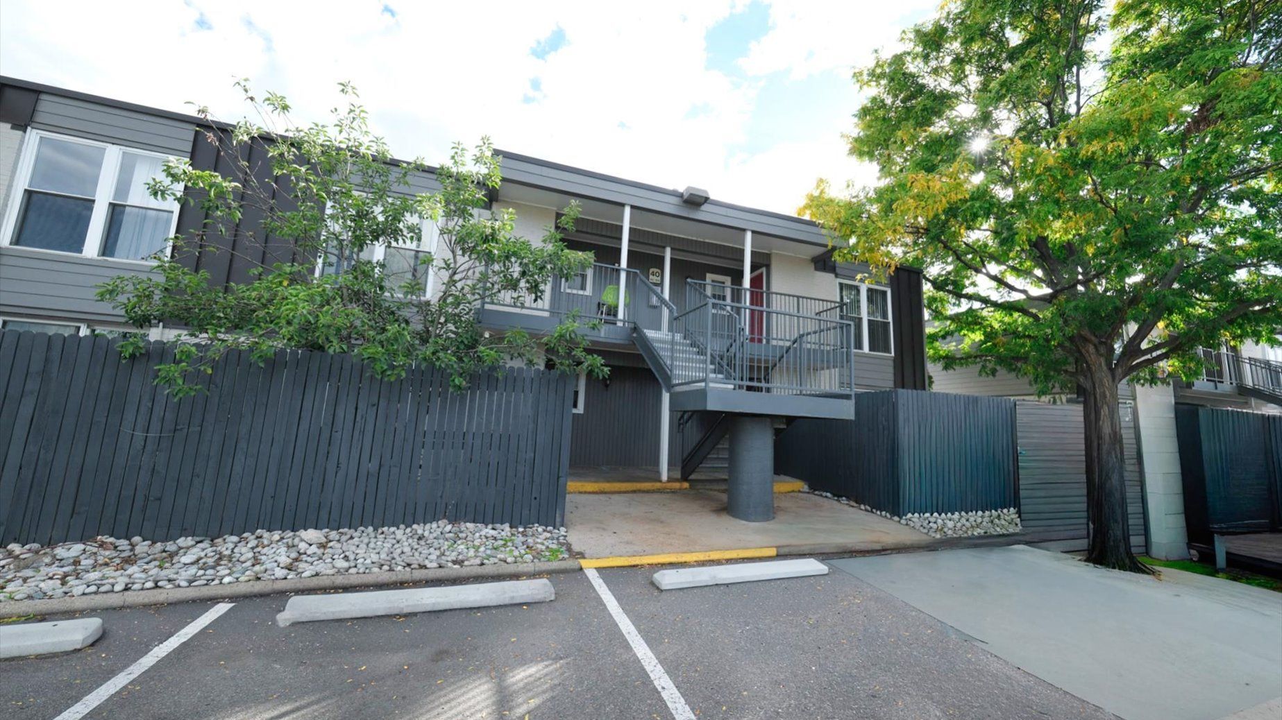 Exterior view of a modern apartment complex with a central staircase and parking.