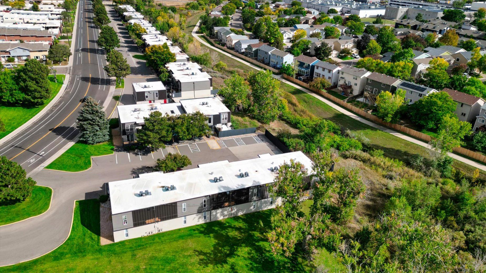 Aerial view of a multifamily apartment complex with buildings, parking, and green spaces.