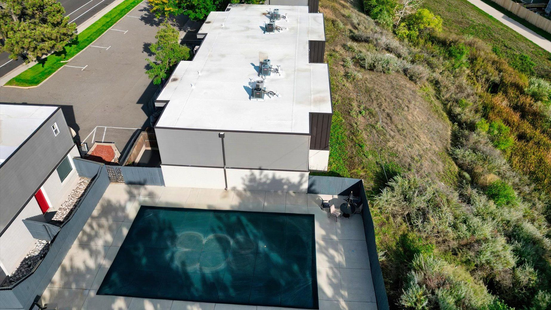 Aerial view of a modern apartment complex showing a flat rooftop and a pool.