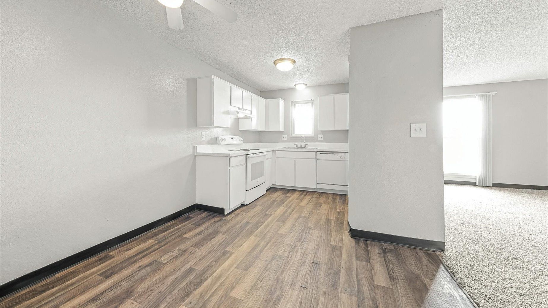 Kitchen in an apartment with white cabinets, stove, and sink.