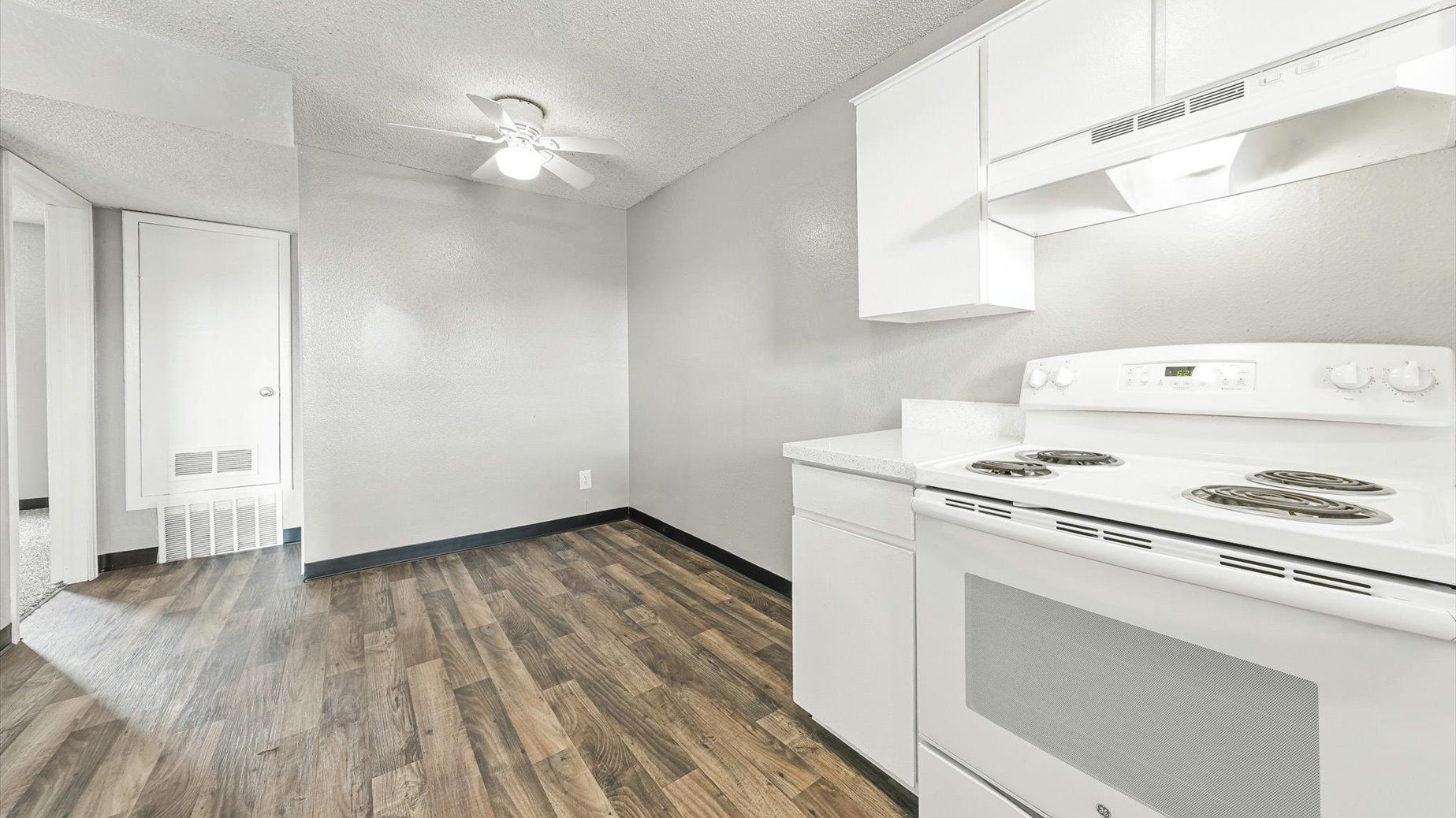 White stove with white cabinets in a compact apartment kitchen.