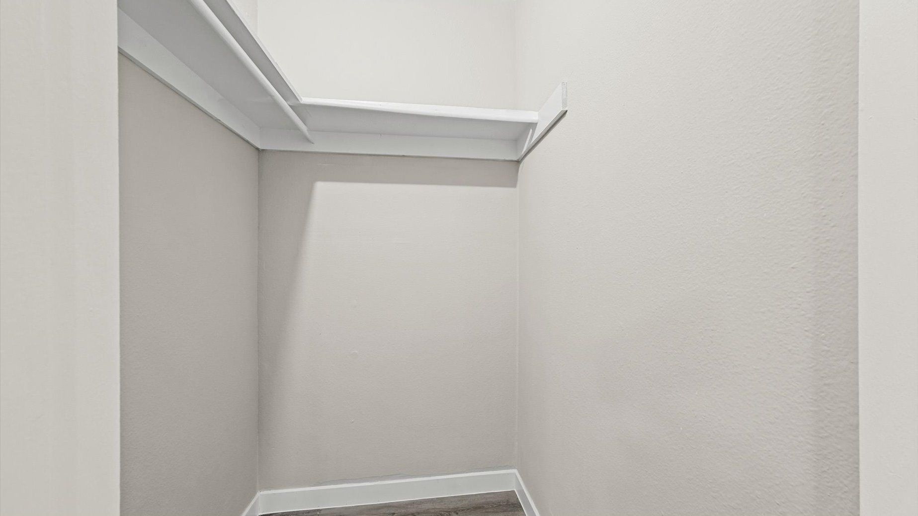 Walk-in closet with a hanging rod and shelf