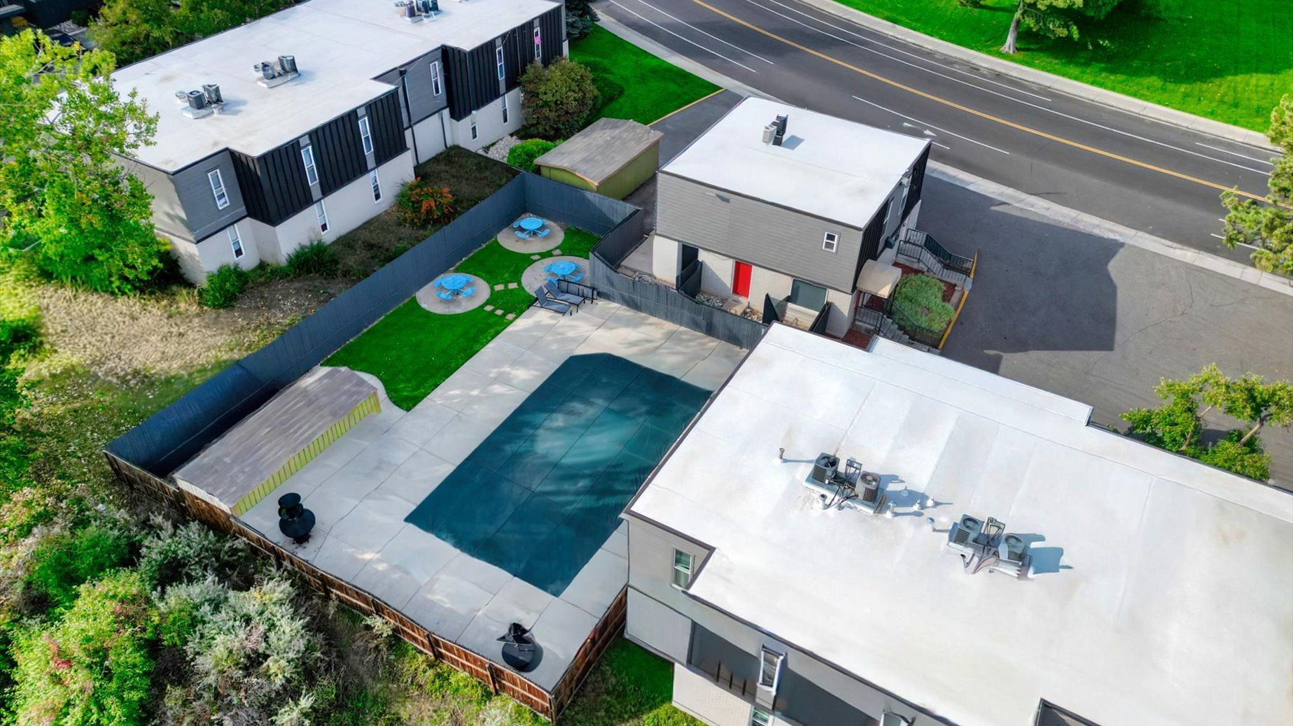 An aerial view of a modern apartment complex courtyard with round seating areas and green turf.