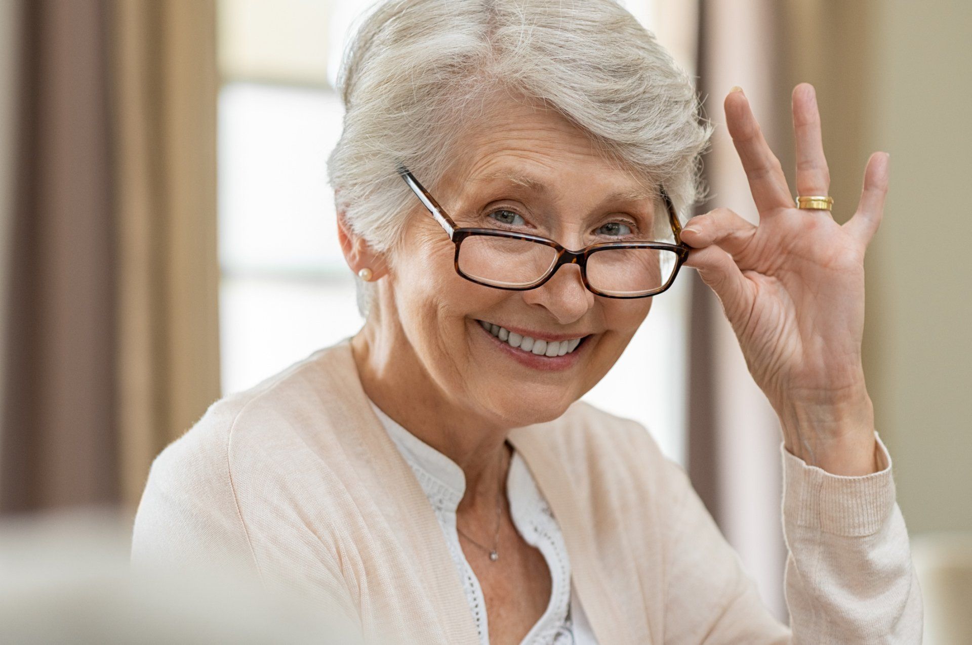 Glasses — Senior woman holding eyeglasses in Highland, IN