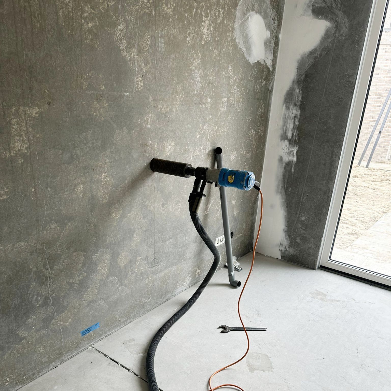 Een stofzuiger wordt in een kamer aan de muur bevestigd.om gaten te boren in beton.