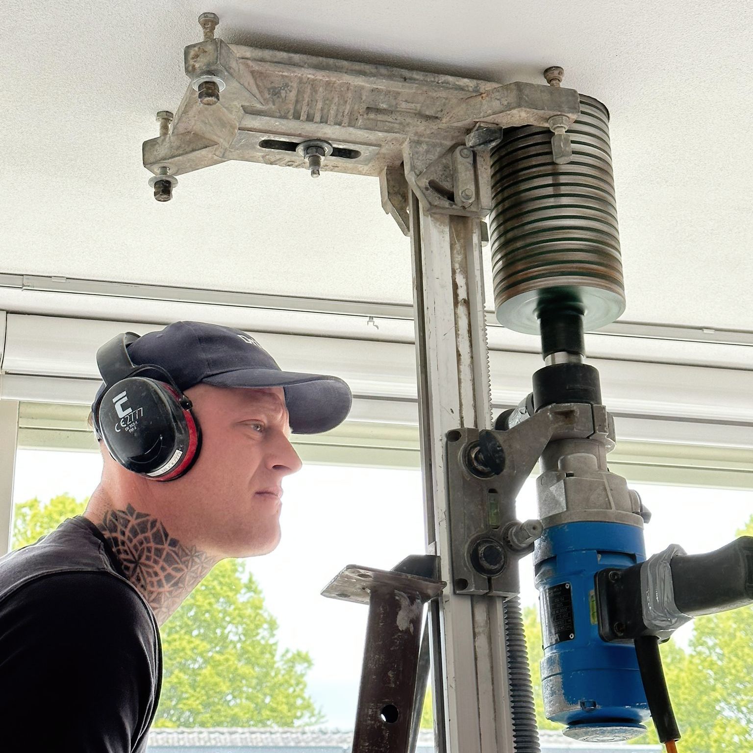 A man wearing headphones is working on a drilling machine