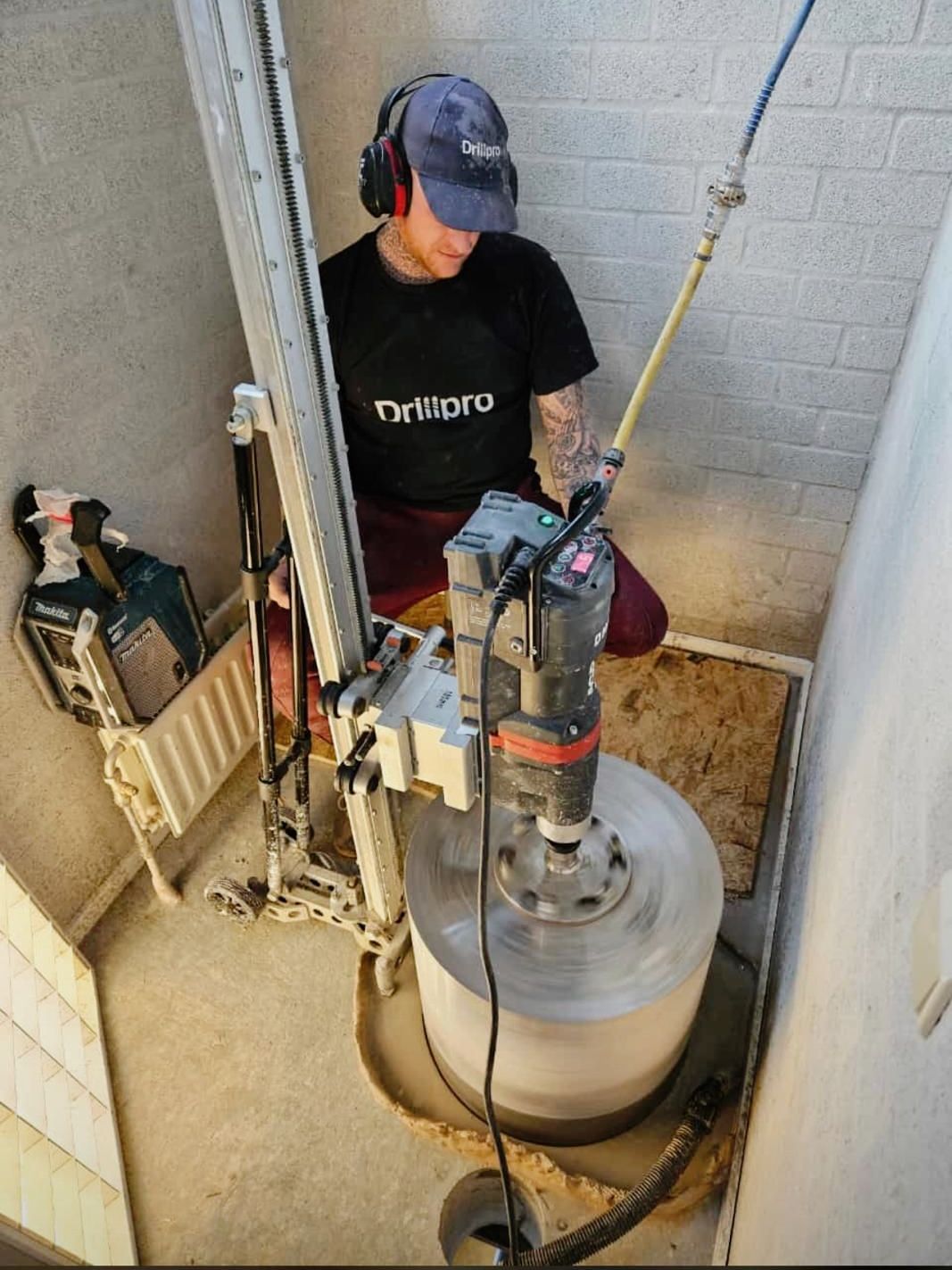 A man is working on a machine in a room drilling concrete 