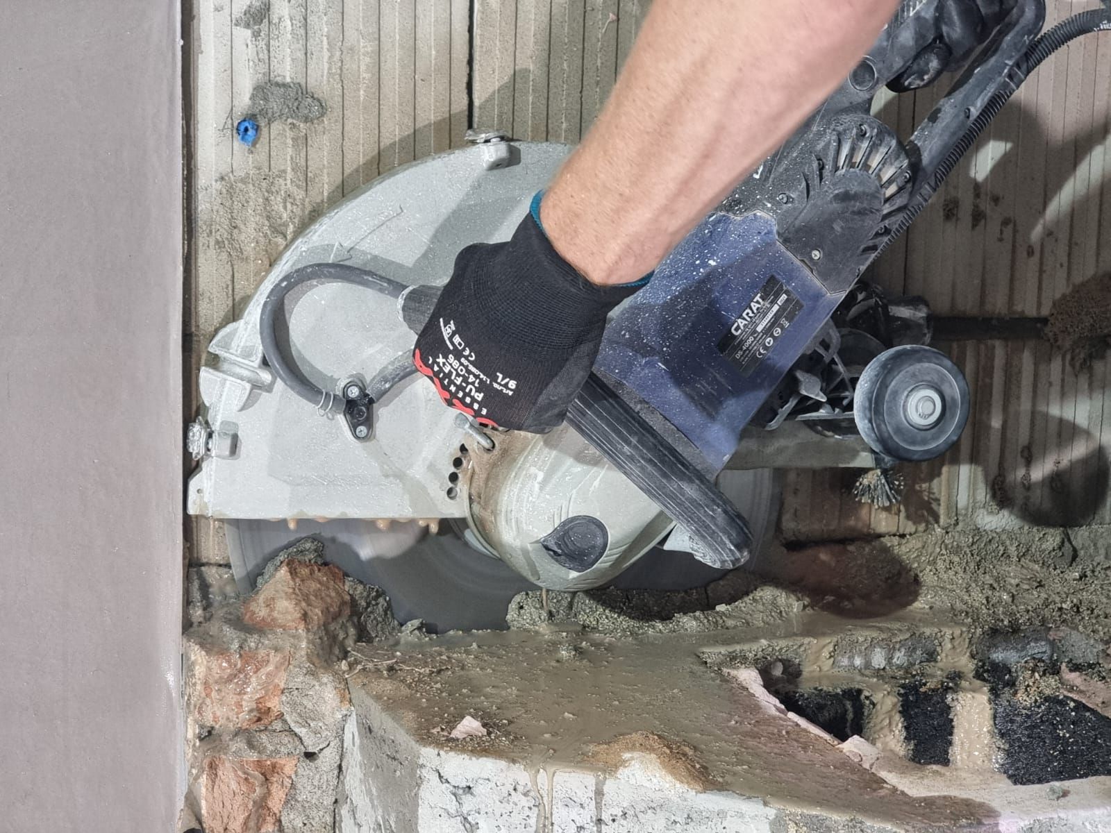 A person is using a circular saw to cut a hole in a wall of concrete 