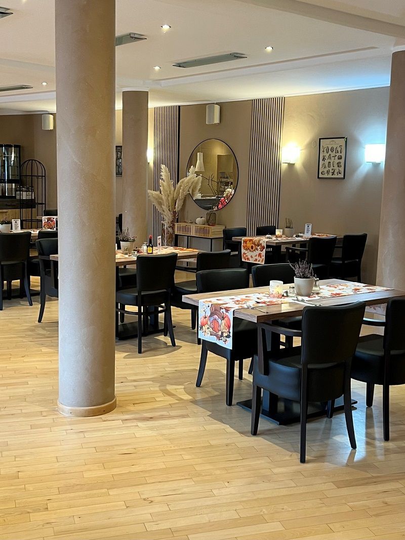 Restaurantinnenraum mit Tischen, Stühlen und beigen Säulen. Beige und braune Wände.