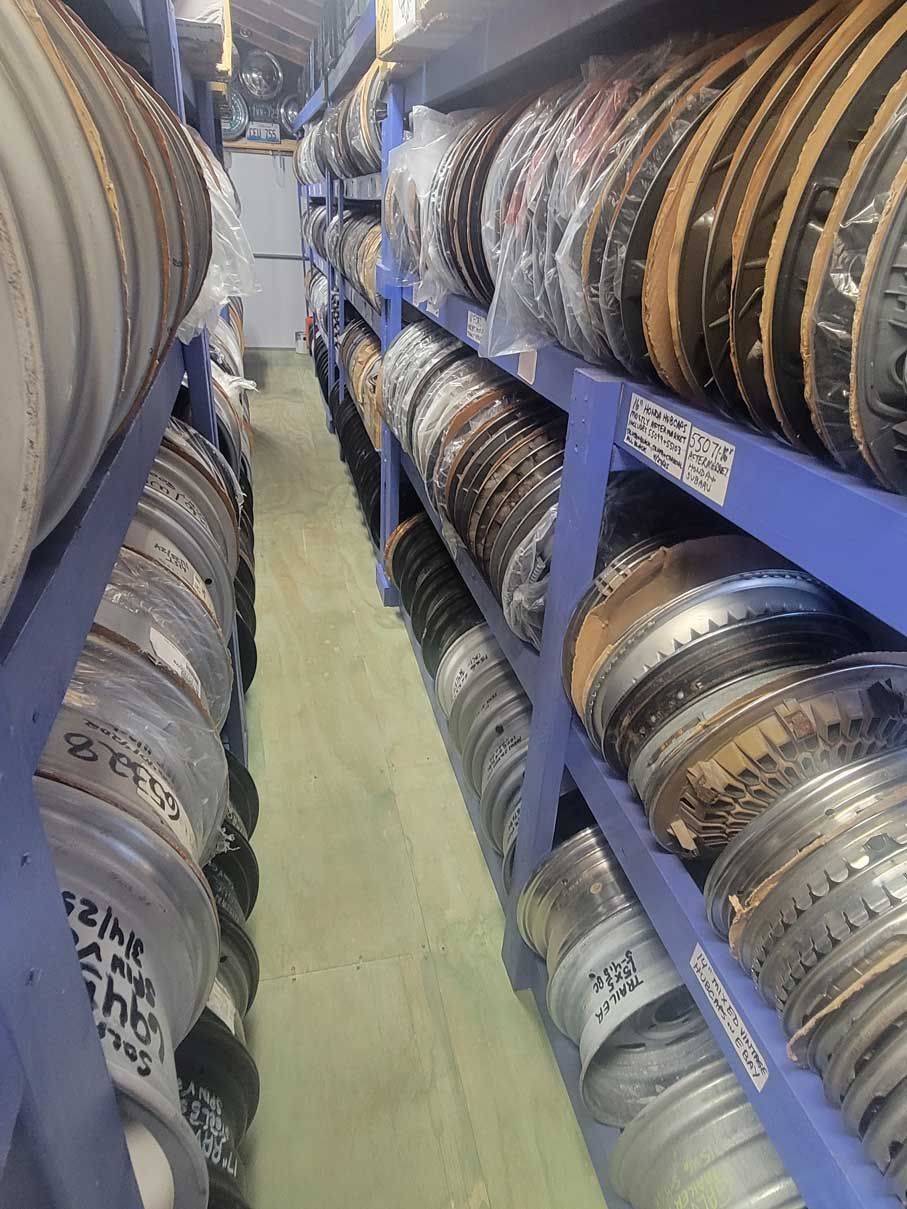 Metal rims stacked on blue shelves in a storage room. Metal rims stacked on blue shelves in a storage room.