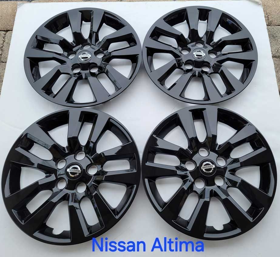 Four black Nissan Altima hubcaps, each with a silver Nissan logo in the center.