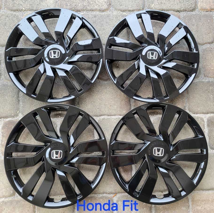 Four glossy black Honda Fit hubcaps arranged in a square.