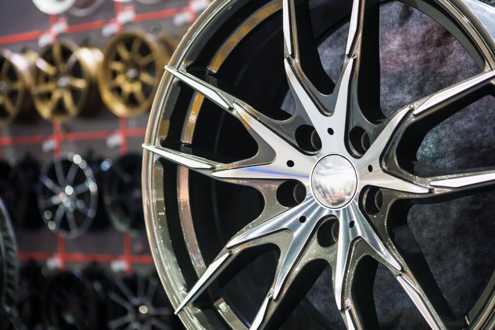 Close-up of a silver and black car wheel rim with a multi-spoke design. Close-up of a silver and black car wheel rim with a multi-spoke design.