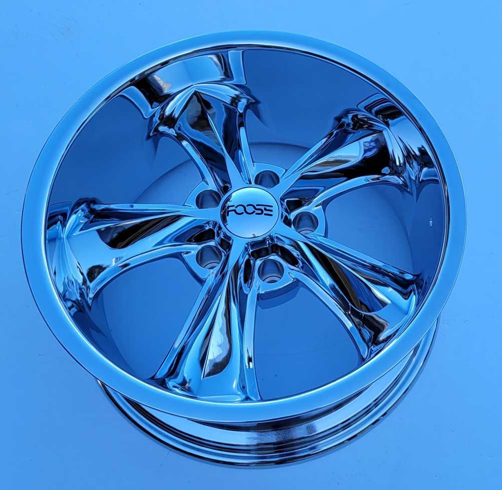 Chrome Foose wheel with five spokes, reflecting a blue environment. Chrome Foose wheel with five spokes, reflecting a blue environment.